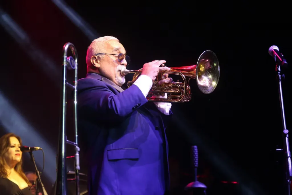Fotografía de Willie Colón tocando el trombón en uno de sus conciertos.