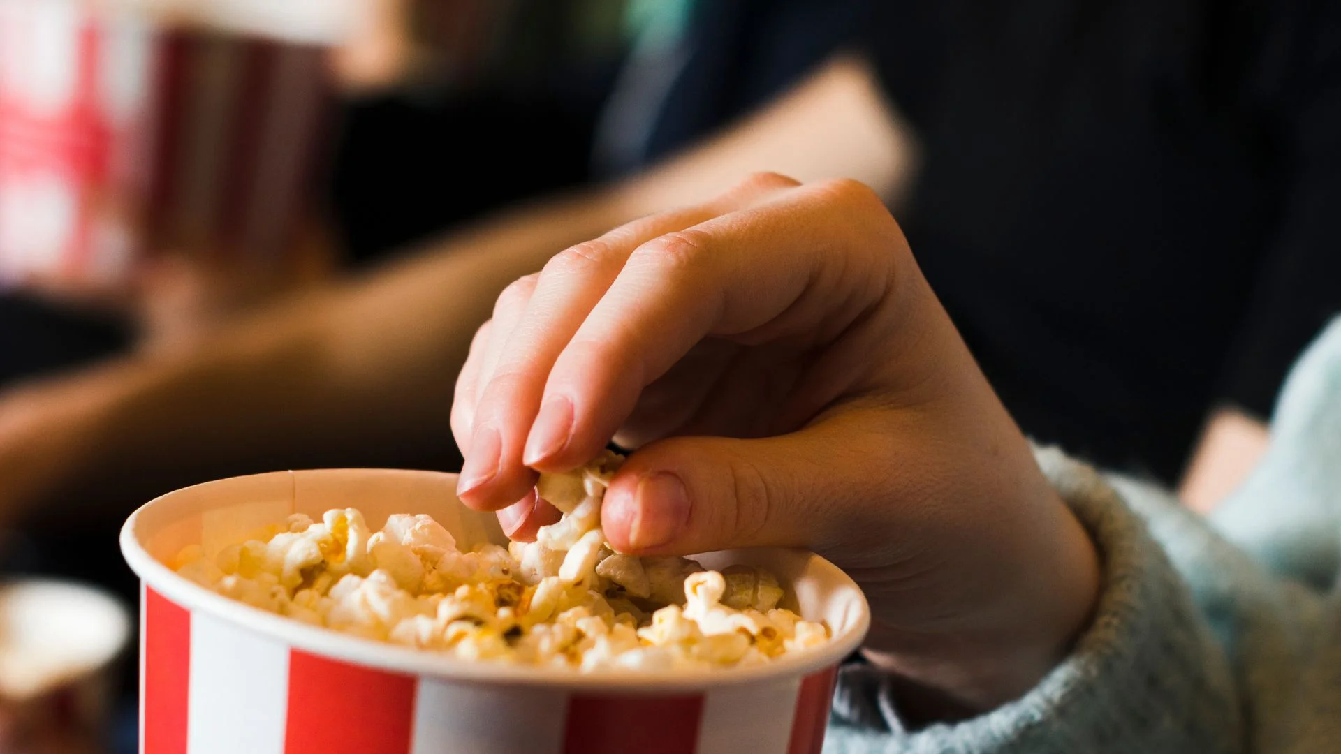 Imagen referencial de persona comiendo palomitas de maíz mientras ve una película en un cine.